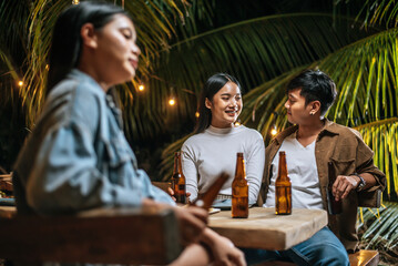 Portrait of Happy Asian friends having dinner party together - Young people toasting beer glasses dinner outdoor  - People, food, drink lifestyle, new year celebration concept.