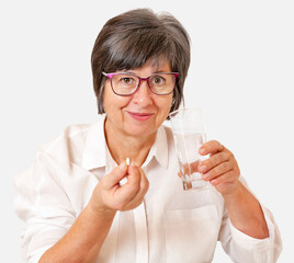 woman taking pills while sitting at the table