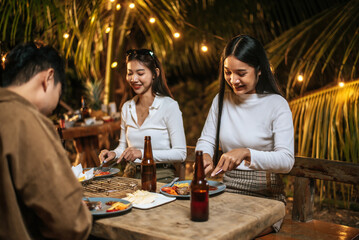 Happy Asian friends cheering with roasted turkey dinner outdoor - Group of people having fun in new year party. People, food and drink lifestyle concept Night Party, people and celebration concept.