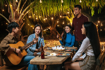 Portrait of Happy Asian group of friends having fun to music dining and drinking together outdoor - Happy friends group toasting beers  - People, food, drink lifestyle, new year celebration concept.