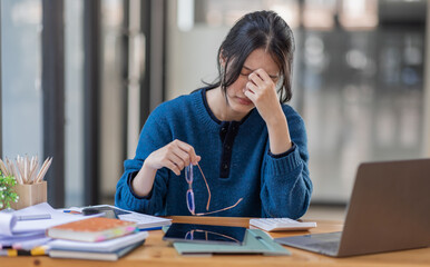 Portrait of tired young business Asian woman work with documents tax laptop computer in office. Sad, unhappy, Worried, Depression, or employee life stress concept.