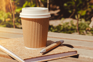 Eco recycling paper cup with coffee or tea on kraft paper with empty paper notebook on wooden...