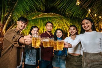 Portrait of Happy Asian friends having dinner party together - Young people toasting beer glasses dinner outdoor  - People, food, drink lifestyle, new year celebration concept.