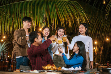 Portrait of Happy Asian friends having dinner party together - Young people toasting beer glasses dinner outdoor  - People, food, drink lifestyle, new year celebration concept.