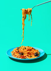Eating italian spaghetti from a plate, isolated on a green background