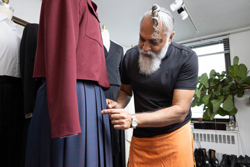 grey hair bearded man wearing skirt designing tailored fashion