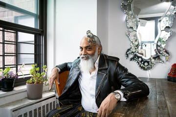 portrait of smiling man with gray hair and beard wearing leather jacket