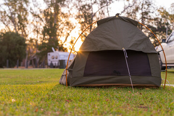 Low angle view on a sleeping swag set up on a grassy area of a campground at sunset