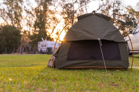 Low angle view on a sleeping swag set up on a grassy area of a campground at sunset