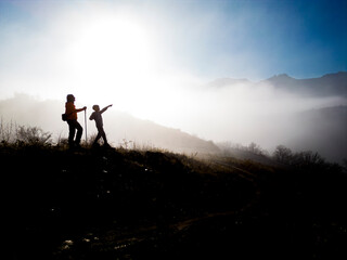father and son watching wonderful foggy scenery while hiking in the mountains