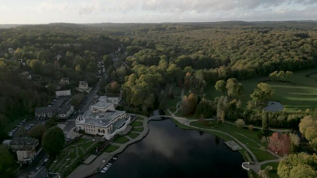Lac de Bagnoles de l'Orne, small lake on edge of Andaines forest, Normandy in France. Aerial forward tilt-up reveal