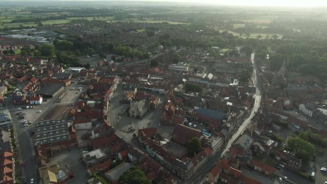 Drone shot puling out off historic English market town centre with church at golden hour sunrise