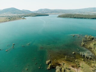 Aerial view on mountain lake. Drone over water reservoir at mountain valley covered with green spring forest. Beautiful view from above on smooth blue surface of mountain lake among highlands. Nobody