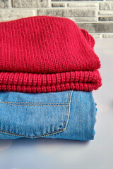 stack blue cotton jeans and raspberry wool sweater on grey, banner concept, close-up