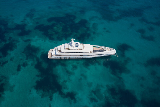 big white mega yacht is anchored on clear blue water top view