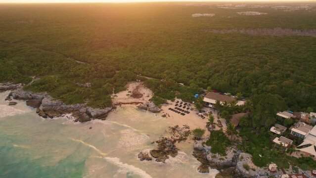A flying back reveal of the famous Gitano Beach Mexican restaurant situated on the Tulum Beach on the Caribbean Sea coastline of Mexico where a dense forest meets the ocean