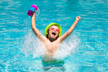 Cute child in hat and sunglasses swim in pool with blue water background. Happy summer holidays. Kid hold cocktail.
