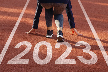Happy new year 2023 symbolizes the start of the new year. Women preparing to run on the athletics...