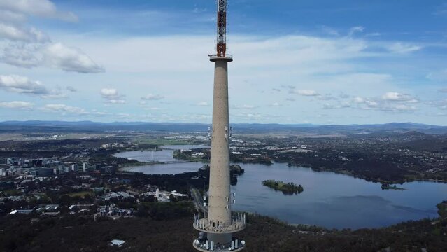 Aerial flyby of Telstra Tower in Canberra, the capital of Australia, showing a panoramic view of Lake Burley Griffin and surrounding landmarks and countryside