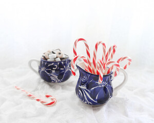Candy canes in a blue ceramic bowl on a white background.