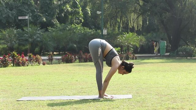 Video of a woman practising Surya Namaskar in a park.