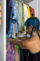 indigenous non-binary artist with blue hair getting dressed