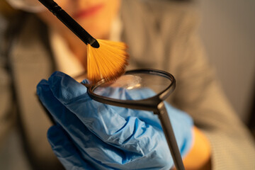 Forensic fingerprint analysis, criminalist woman collects latent fingerprints using powder on...