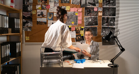 Private detectives working together reading papers of criminal case, systematizing information and...
