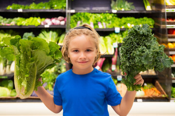 Kid with vegetables at grocery store. Healthy food for kids. Portrait of smiling little child with shopping bag at grocery store or supermarket.