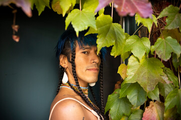 indigenous non-binary artist in garden doorway with vine