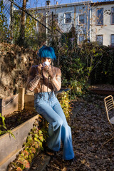 indigenous non-binary artist drinking tea in urban garden in autumn