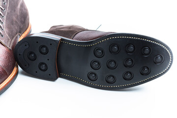 Footwear Ideas. Premium Dark Brown Grain Brogue Derby Boots Made of Calf Leather with Rubber Sole Placed Reversed With Sole Exposed Over White Background.