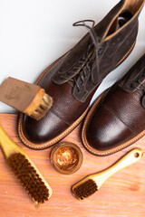 Upper View of Various Shoes Cleaning Accessories for Dark Brown Grain Brogue Derby Boots Made of Calf Leather with Special Tools.