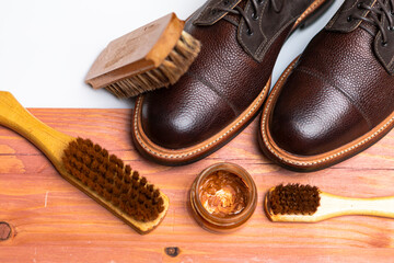 Upper View of Various Shoes Cleaning Accessories for Dark Brown Grain Brogue Derby Boots Made of Calf Leather with Special Tools.