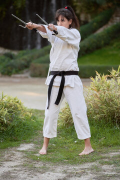 Female karate fighter with black belt practicing karate outdoors in the nature. Sports and martial arts concept.