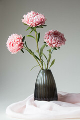 Bright pink flowers in a glass vase on  a neutral background. Elegant flower arrangement with silk...