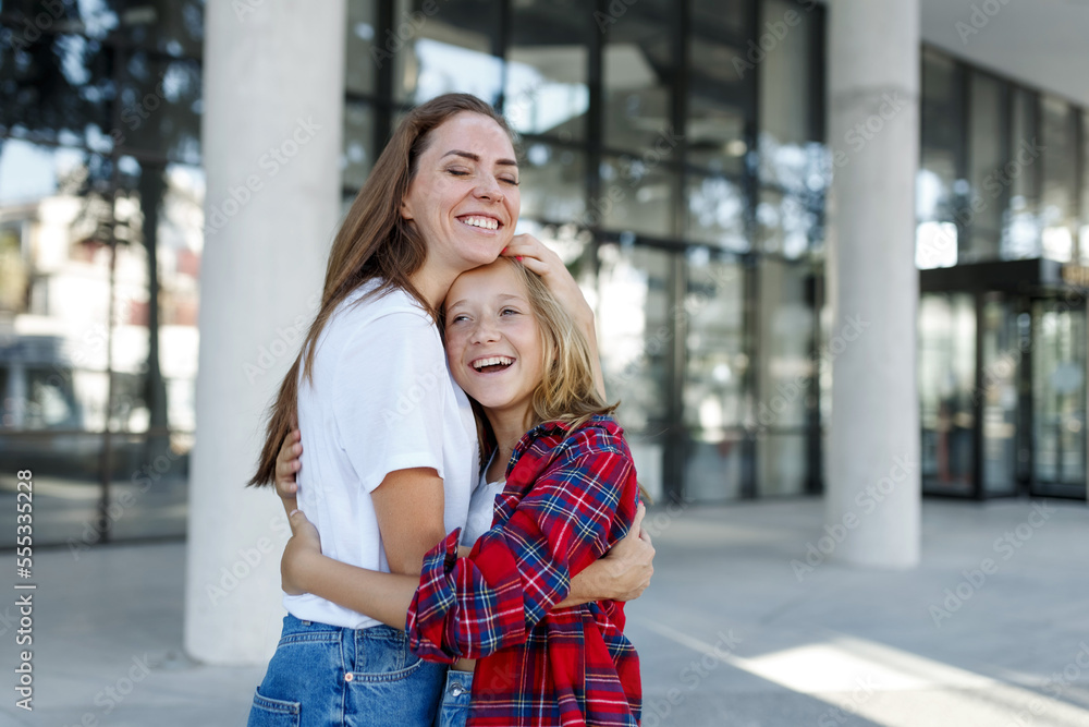 Wall mural mother hugs with daughter schoolgirl outdoors. cheerful teen and female in good mood. love and famil