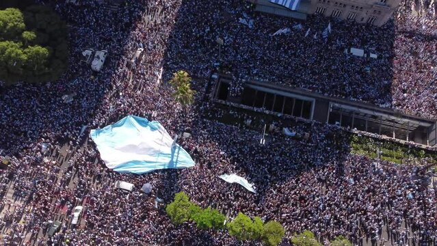 the supporters of the argentine football team celebrate the victory of the world championship in the streets of buenos aires carrying a huge flag above their heads