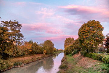 Small river at autumn sunset, trees and clouds.