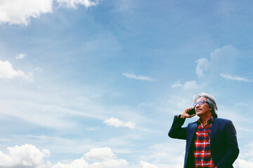 senior business man using mobile phone communication on blue sky white cloud nature background
