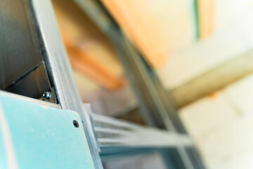 The beginning of the process of sheathing the frame with drywall. One sheet of moisture-resistant drywall is screwed to a metal profile in a close-up shot against a blurred background