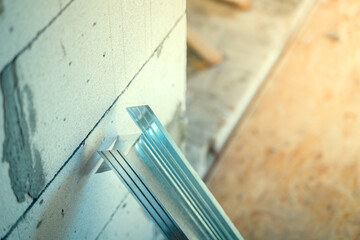 Close-up of a metal profile prepared for a frame wall. Cropped and curved end of a metal U profile on a blurred background
