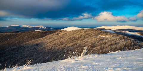 panorama of snow-capped mountains at sunset during a cold winter; mighty mountain peaks in the Polish Bieszczady mountains; mountain vegetation covered with snow