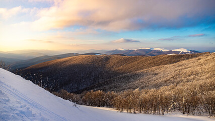 panorama of snow-capped mountains at sunset during a cold winter; mighty mountain peaks in the Polish Bieszczady mountains; mountain vegetation covered with snow