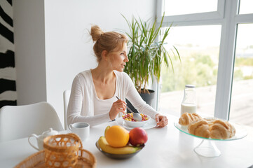 Young woman enjoying healthy breakfast on home kitchen