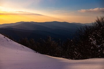 panorama of snow-capped mountains at sunset during a cold winter  mighty mountain peaks in the Polish Bieszczady mountains  mountain vegetation covered with snow © Lens Down Under