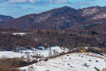 panorama of krywe village in polish bieszczady mountains by the san river; old destroyed orthodox church on the hill in snowy winter weather