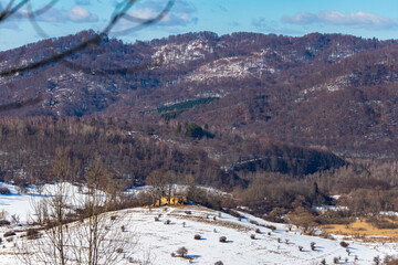 panorama of krywe village in polish bieszczady mountains by the san river  old destroyed orthodox church on the hill in snowy winter weather © Lens Down Under
