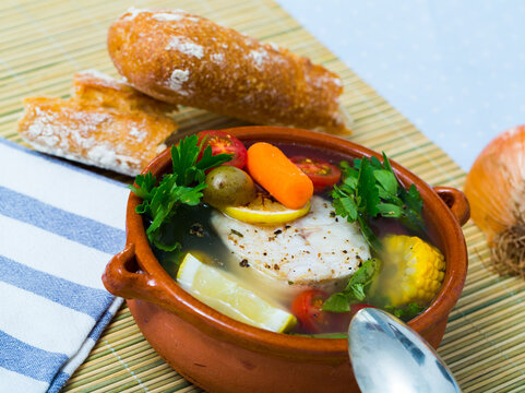 Fisher soup from codfish. Recipe: boil broth from fish head, add potatoes, carrots, shallots, corn, fish fillets or steak 200 g, season with salt, pepper. Then cook in oven at 200 deg for 40min