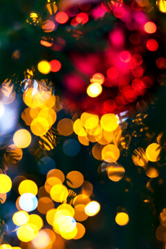 Blurry garland lights on a dark background. Festive Christmas and New Year background. Soft focus. Image toned in color of the year 2023 viva magenta.